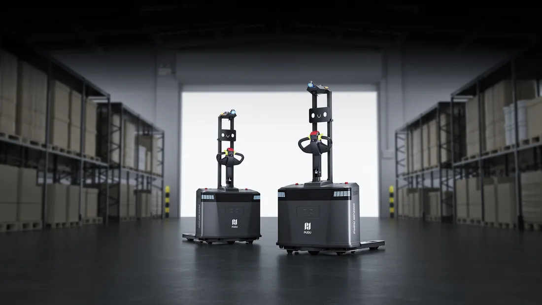 Two PUDU MP2000 autonomous pallet trucks side by side in a warehouse aisle between pallet racking, with a bright open roller door behind
