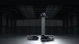 PUDU T600 Underride low-profile chassis robot beside the PUDU T600 Upright with its tall column, face display screen and handlebars, in a dark, empty warehouse